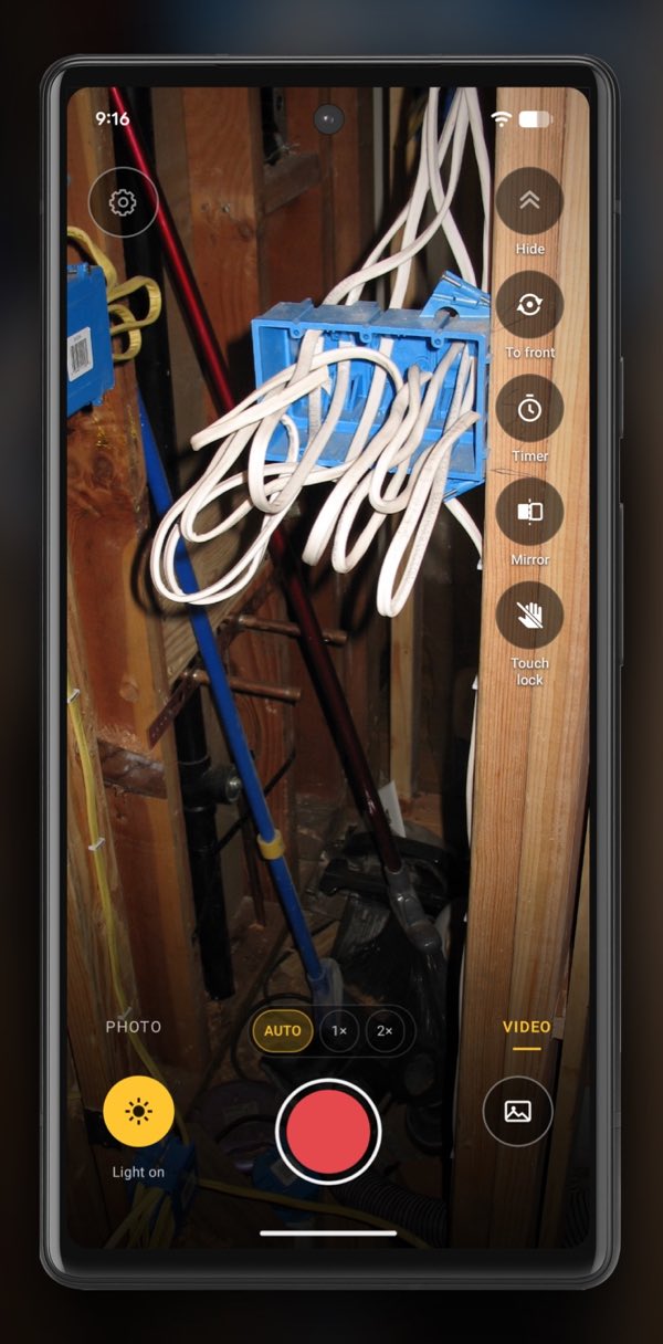 InspectCam in VIDEO mode on an Android phone, held up to an open stud bay at the electrical rough-in: blue boxes on the studs with cable looped out of them, the nearest box brightest in the phone’s light. The red record button is ready and Light on is lit at the bottom left.