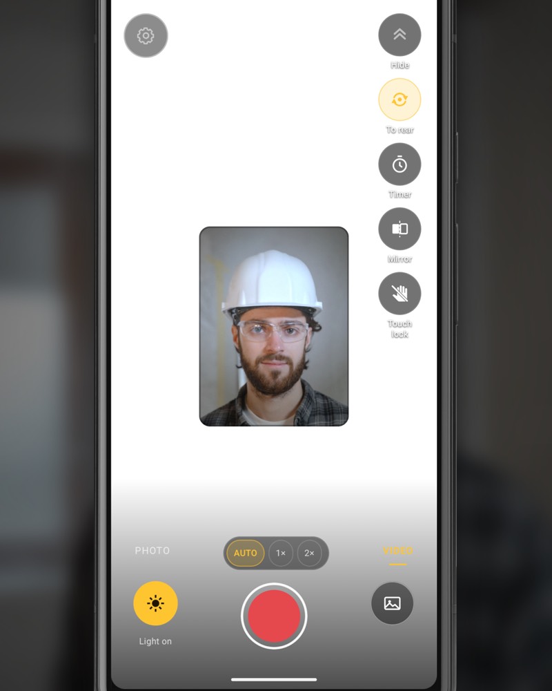 InspectCam on the front camera in video mode: the screen is white around a small window showing a worker in a hard hat and safety glasses.