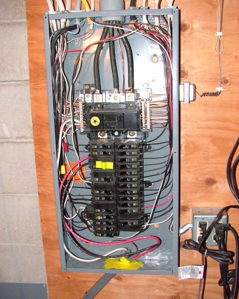 A basement breaker panel with its cover off: two columns of breakers and the wires running into them.