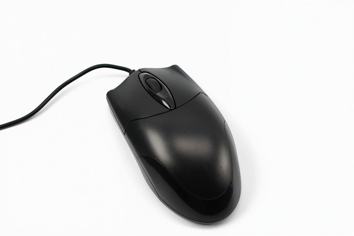 A plain black wired USB computer mouse on a white surface.