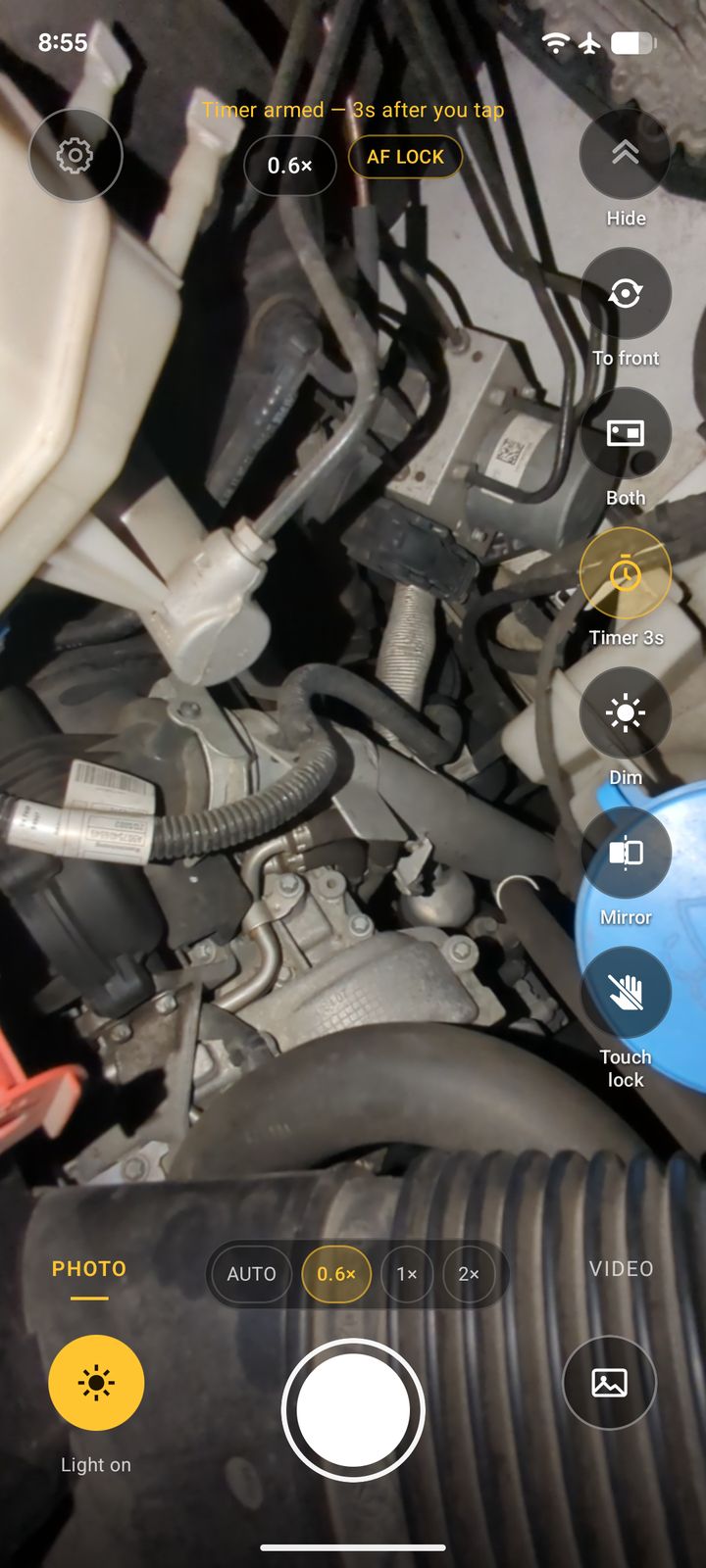 A real InspectCam screenshot: the phone's light on inside a dark engine bay, zoomed out to 0.6×, with the Photo, Video and Light on controls along the bottom.